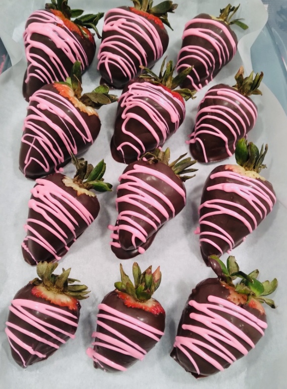 Fresh strawberries dipped in dark chocolate and drizzled with pink chocolate, arranged on parchment paper for Valentine’s Day.
